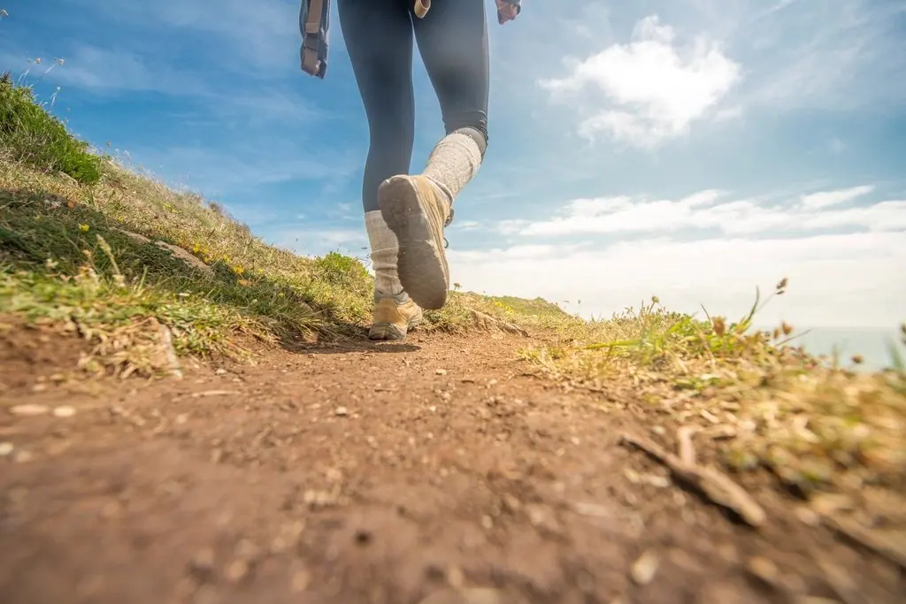 Walking boots on a dirt track along a grassy hillside